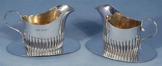 A pair of Edwardian demi fluted silver cream jugs on integral stands, length 115mm, weight 6.5oz/205grms.